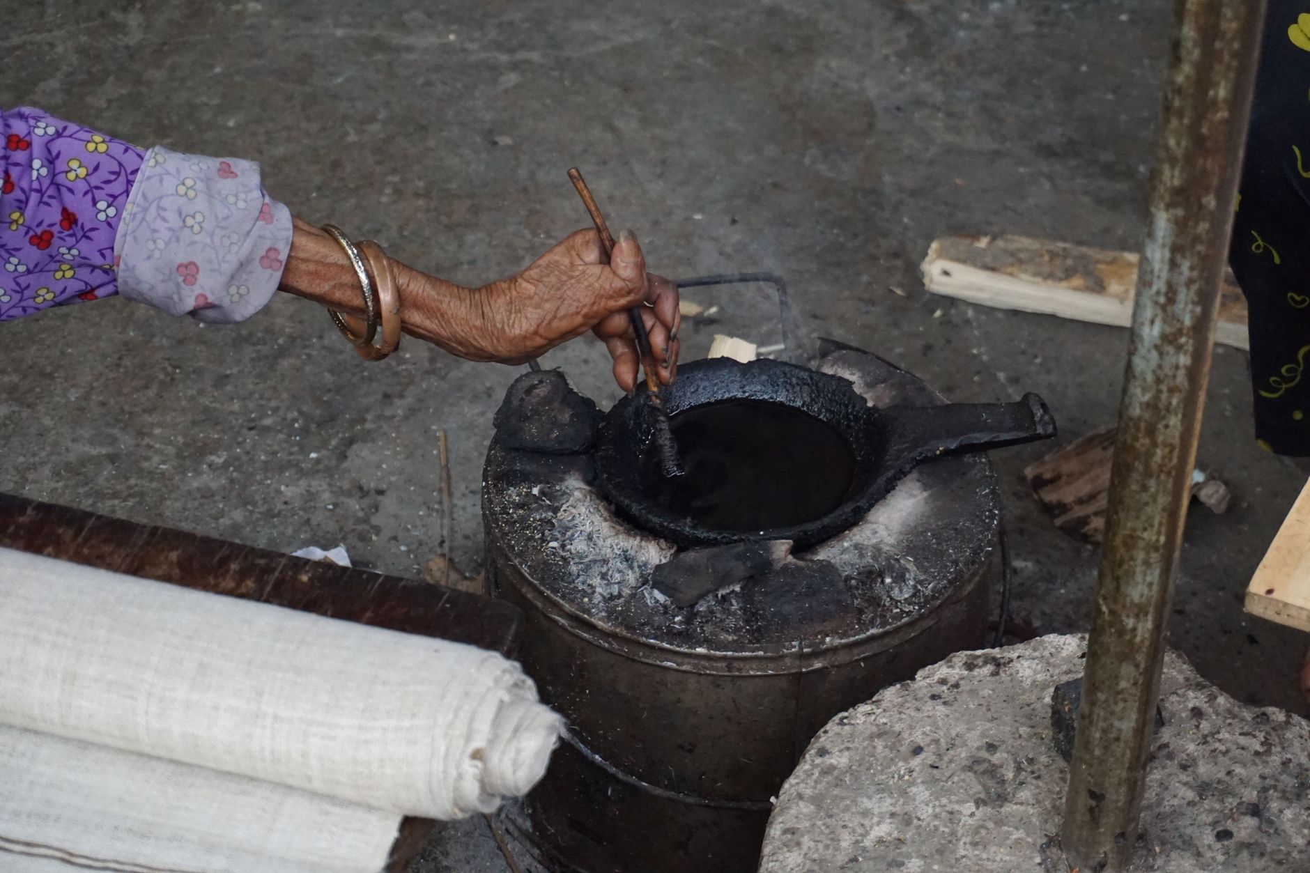 Woman stirring a pot of onion-skin dye as part of natural fabric dyeing at home UK