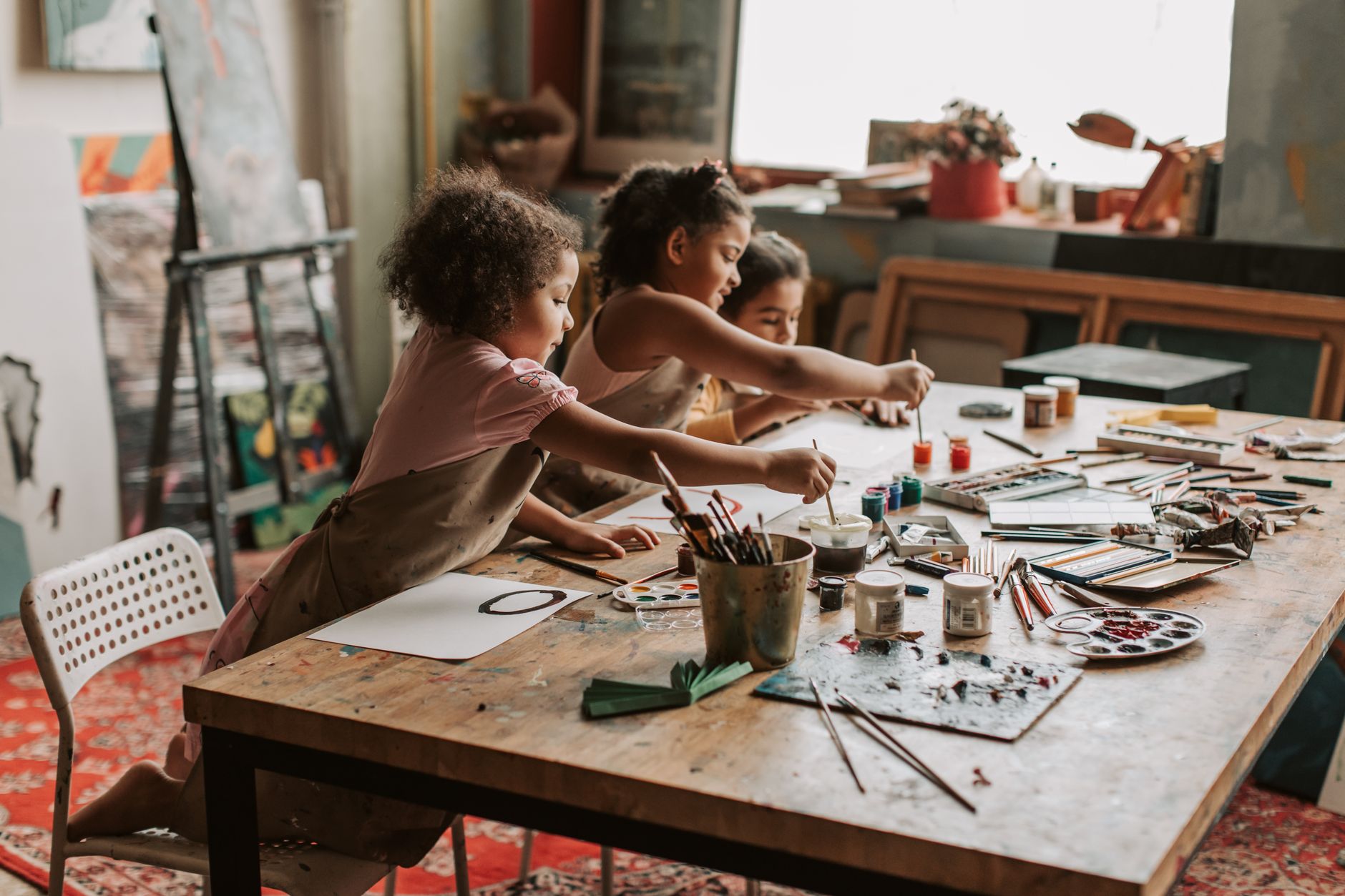 Children taking part in kids art workshop ideas during UK school holidays, painting colourful fruit on paper