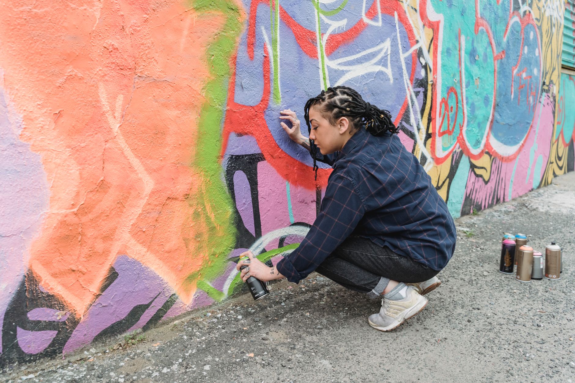 Detail of a brush applying exterior paint during outdoor mural painting on a UK garden fence