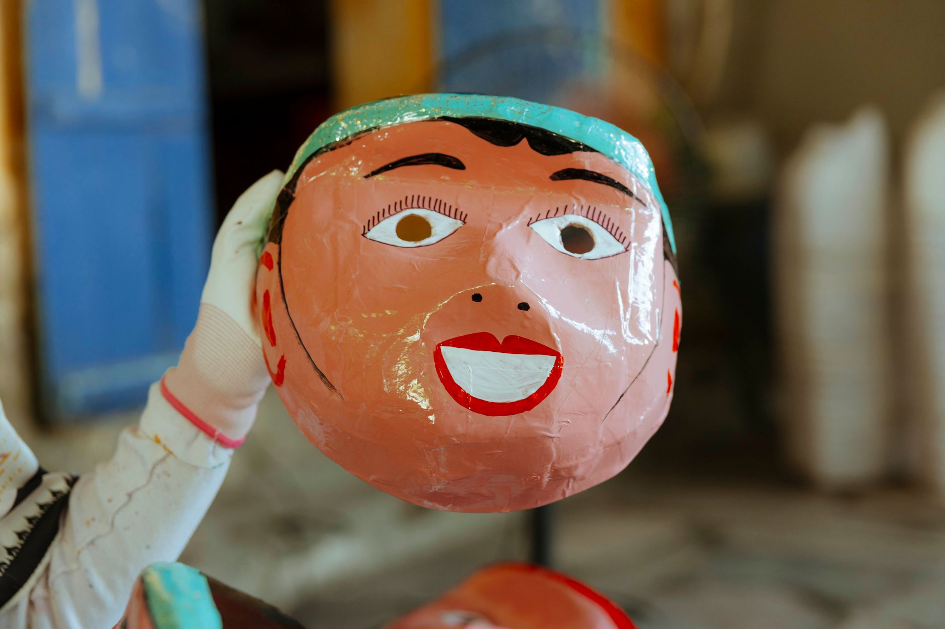 Hands painting a papier-mâché fruit sculpture with vivid yellow acrylic paint